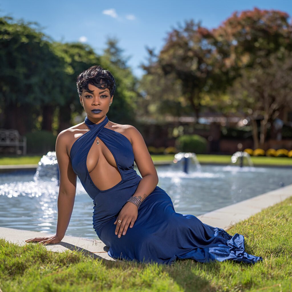 Model in a flowing blue gown beside a fountain, photographed by Daring Leaderman
