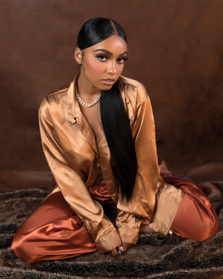 Fashion portrait in bronze satin seated on a warm backdrop