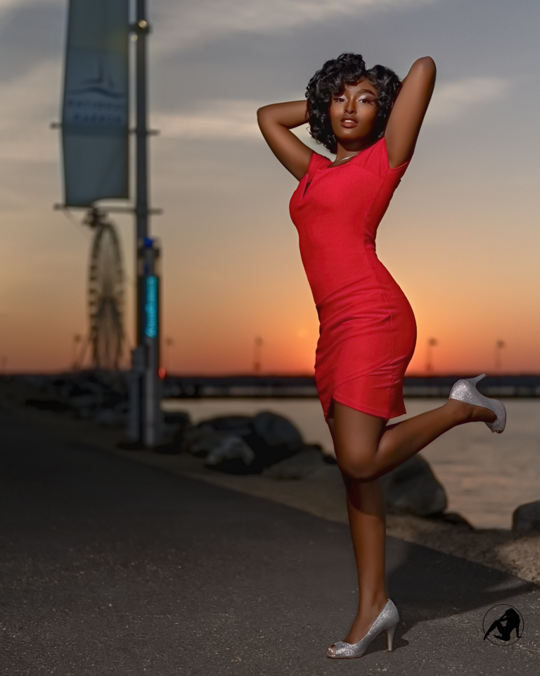 Model in a red dress caught mid-leap against a sunset sky